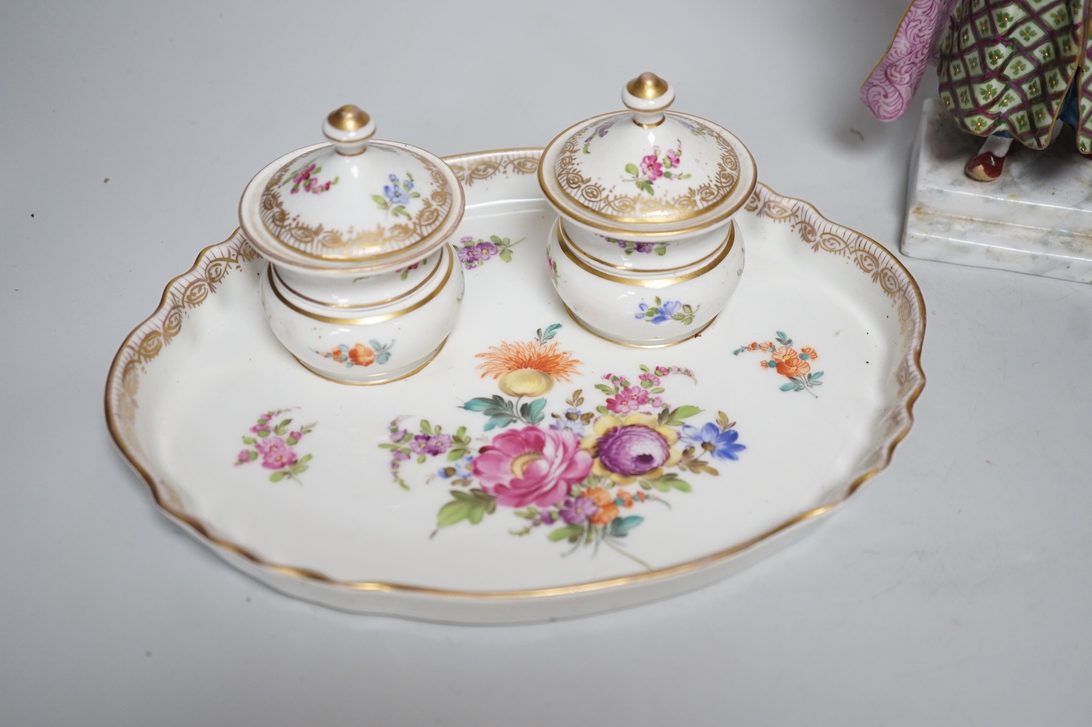 A 19th century German Inkstand with two pots and covers painted with flowers, 24cm wide, and a Volkstedt figure of an eastern European woman holding a bird	